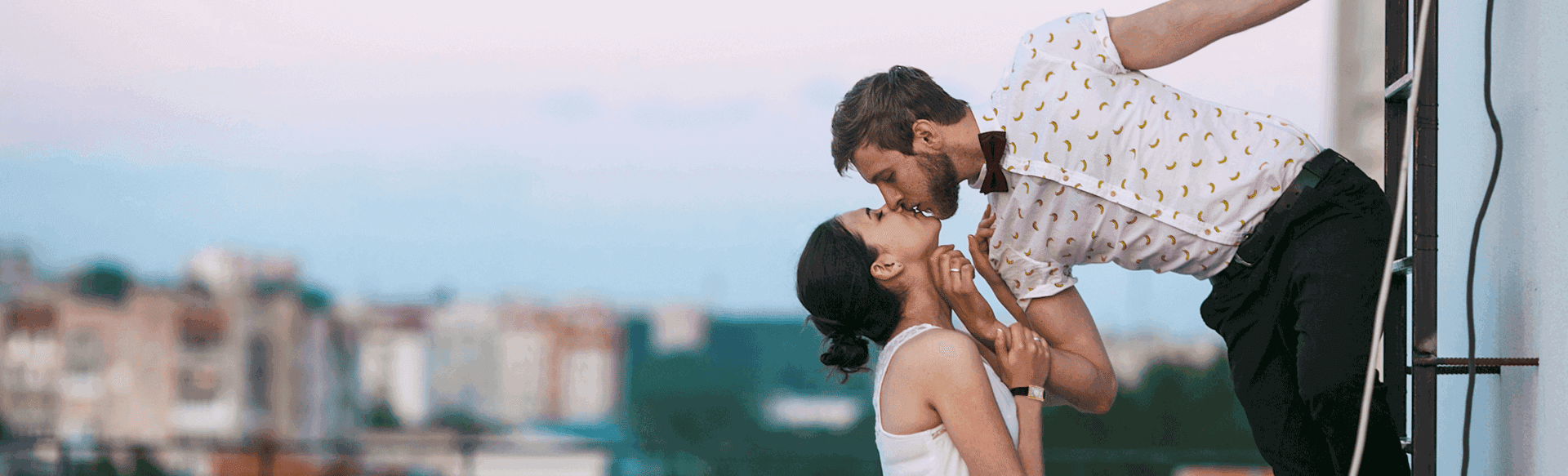 Couple kissing in front of sunset background.