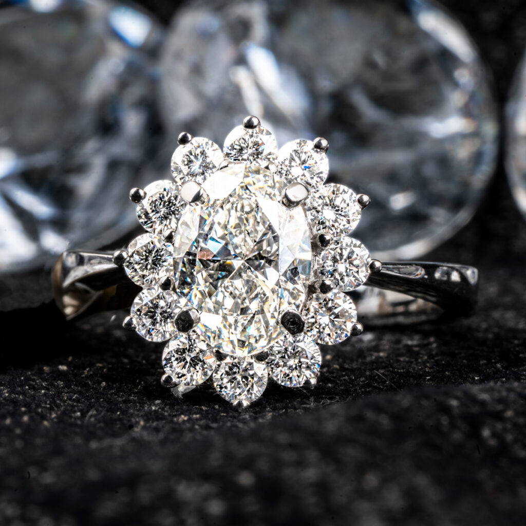White gold cocktail ring centered with an oval diamond surrounded by a diamond halo.