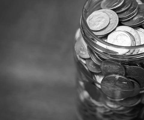 Mason jar filled with silver coins on a wooden table.