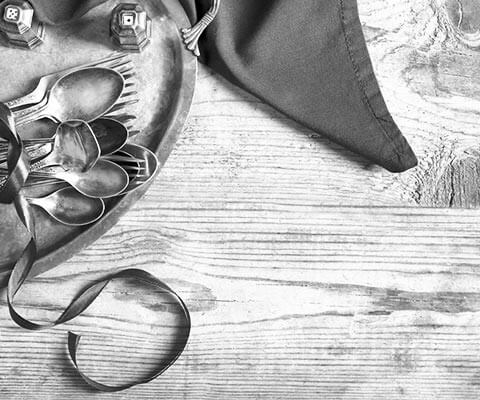 Several pieces of silver flatware sitting on a tray on a wooden table.