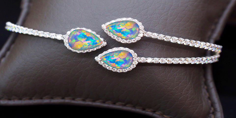 White gold open cuff bracelet set with pear cut opals surrounded by diamond haloes.