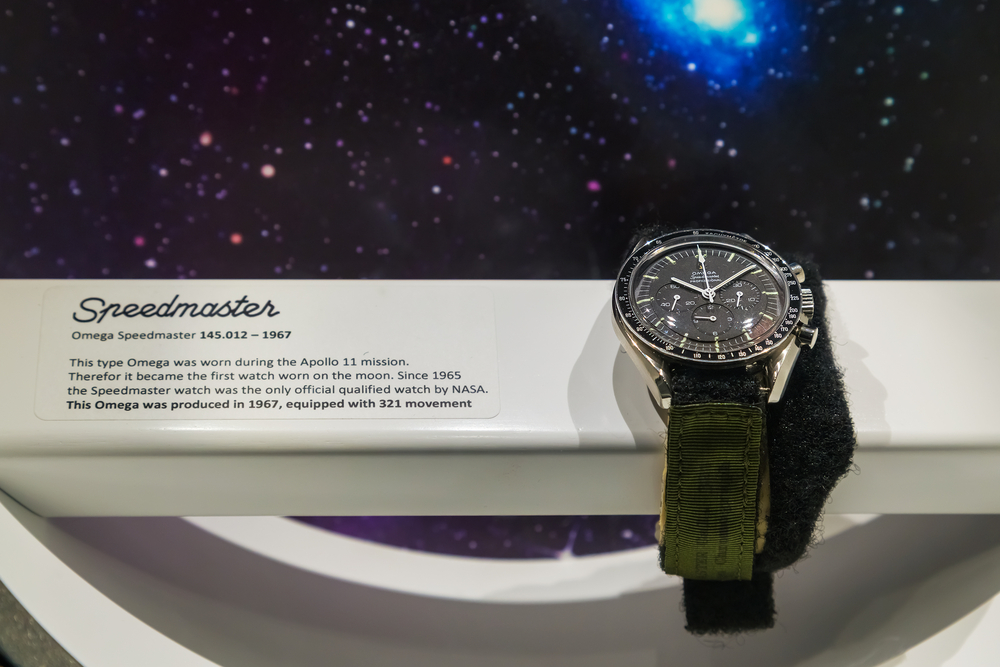 1967 Omega Speedmaster in stainless steel with a green Nato strap on museum display.