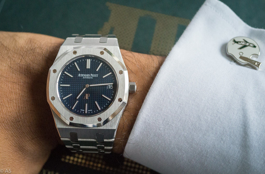 Stainless steel Audemars Piguet with black textured dial on mans wrist.