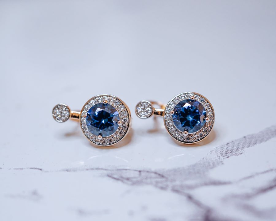 Yellow gold earrings centered with blue sapphire surrounded by diamond halos.