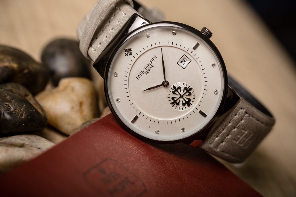 Men's Patek Phillipe in stainless steel with a white dial and a grey leather strap.