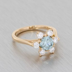 Yellow gold ring centered with a blue gemstone and diamonds.