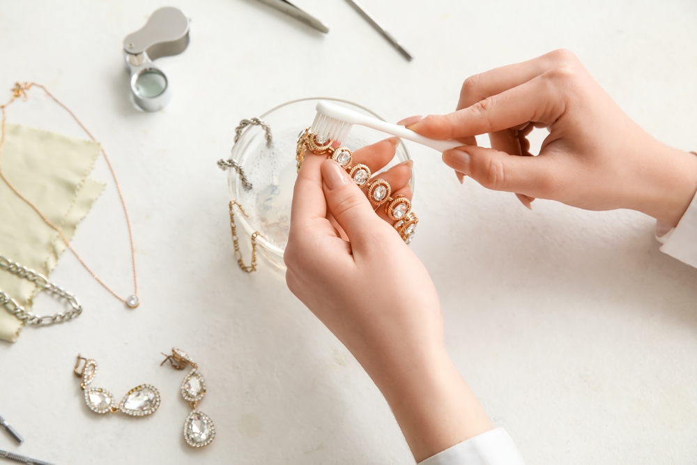 Woman brushing her fine jewelry with toothbrush.