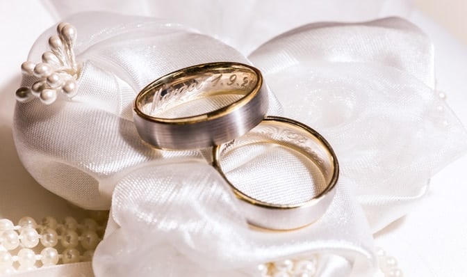 Two engraved weddings bands on a white fabric background.