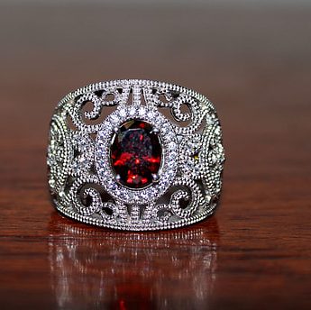 White gold filigree wide band centered with garnet.