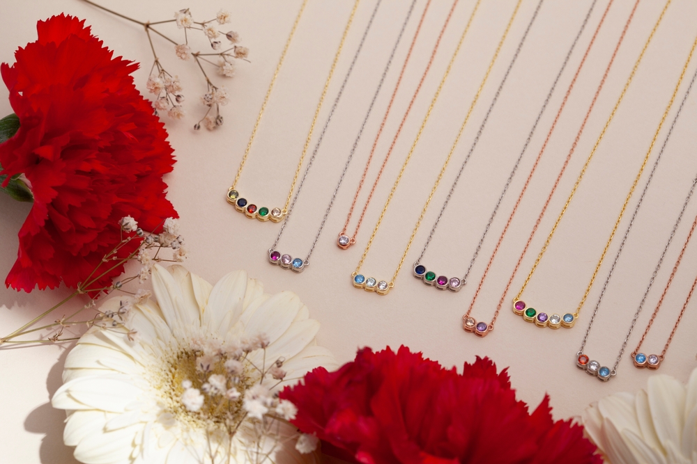 9 necklaces in rose, white, and yellow gold each set with several round cut gemstones of varying rainbow colors.