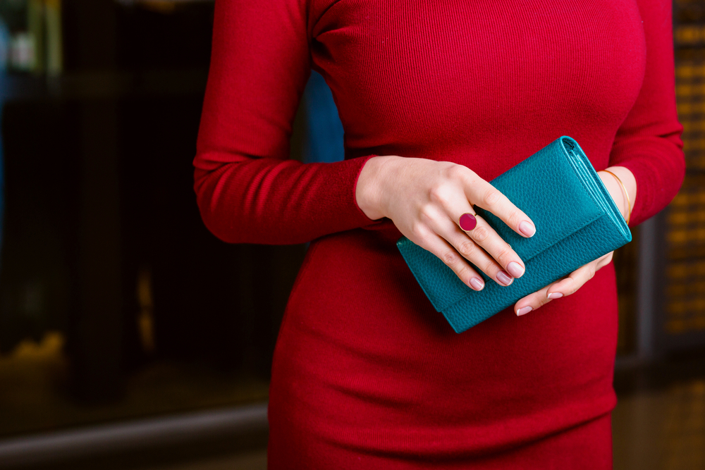 Woman in red dress wearing right-hand cocktail ring set with red center stone.