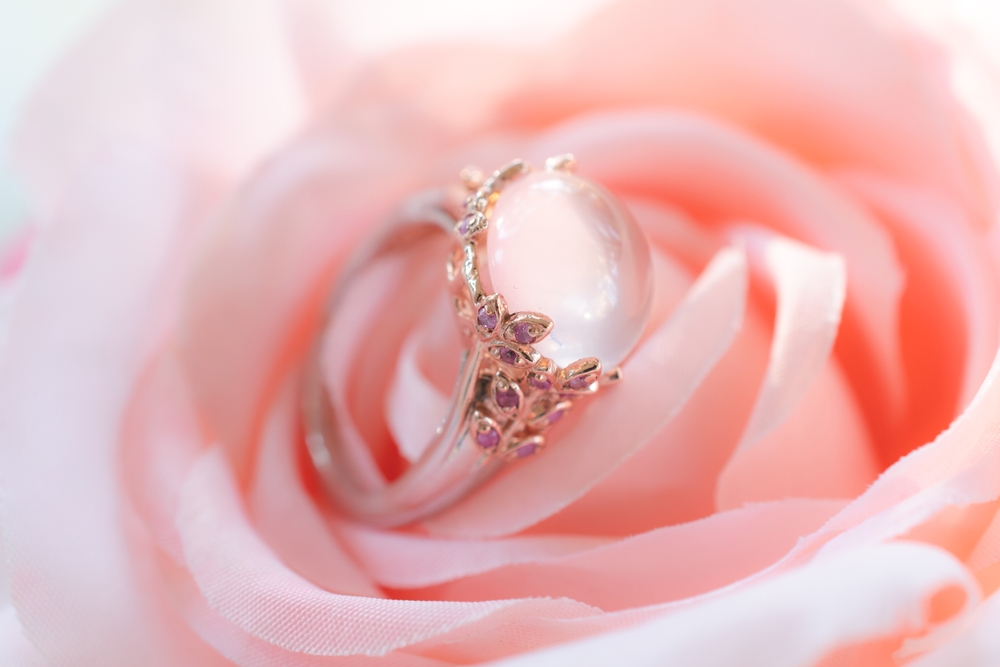 Rose gold engagement ring set with pink sapphires on a pink rose.