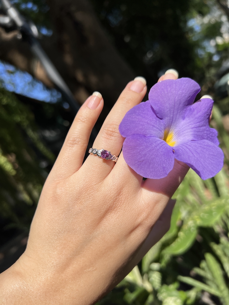 Woman with amethyst engagement ring holding purple flower.