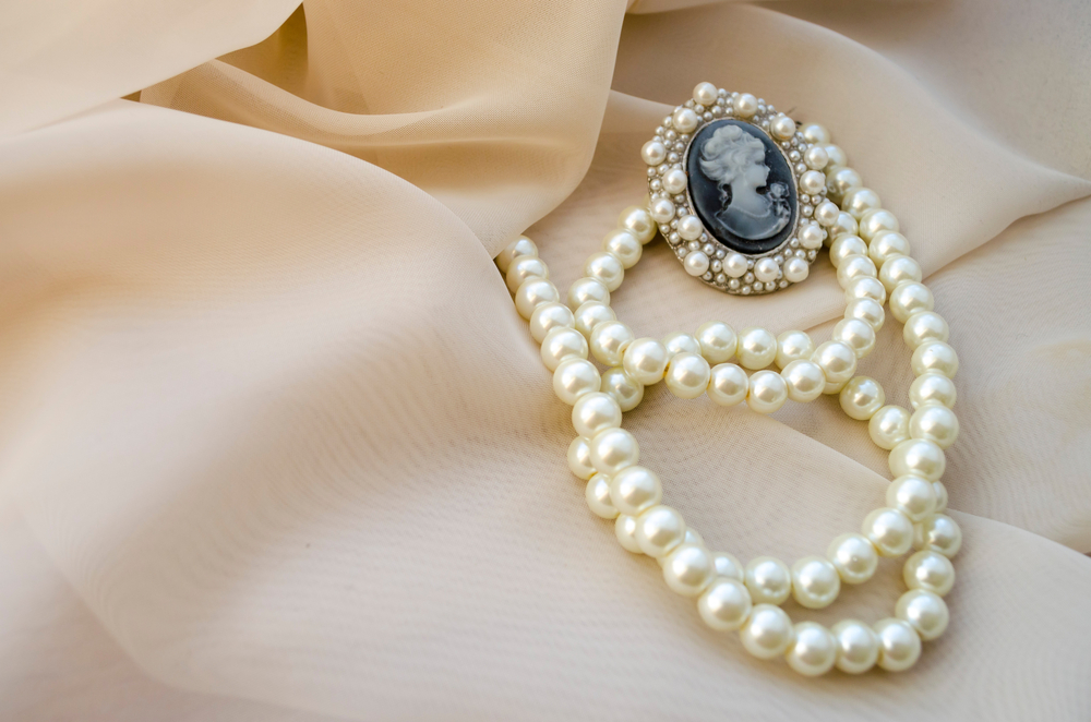 Vintage pearl strand necklace centered with a blue gemstone pendant.