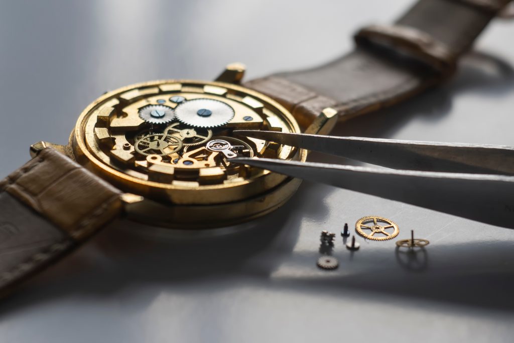 Watchmaker using tweezers to work on inner gears and crystals of a fine watch.