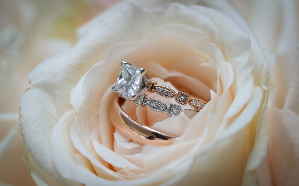 Rose gold engagement ring centered with a solitaire princess cut diamond and alternating princess and round cut diamonds in the band with a matching diamond wedding band.