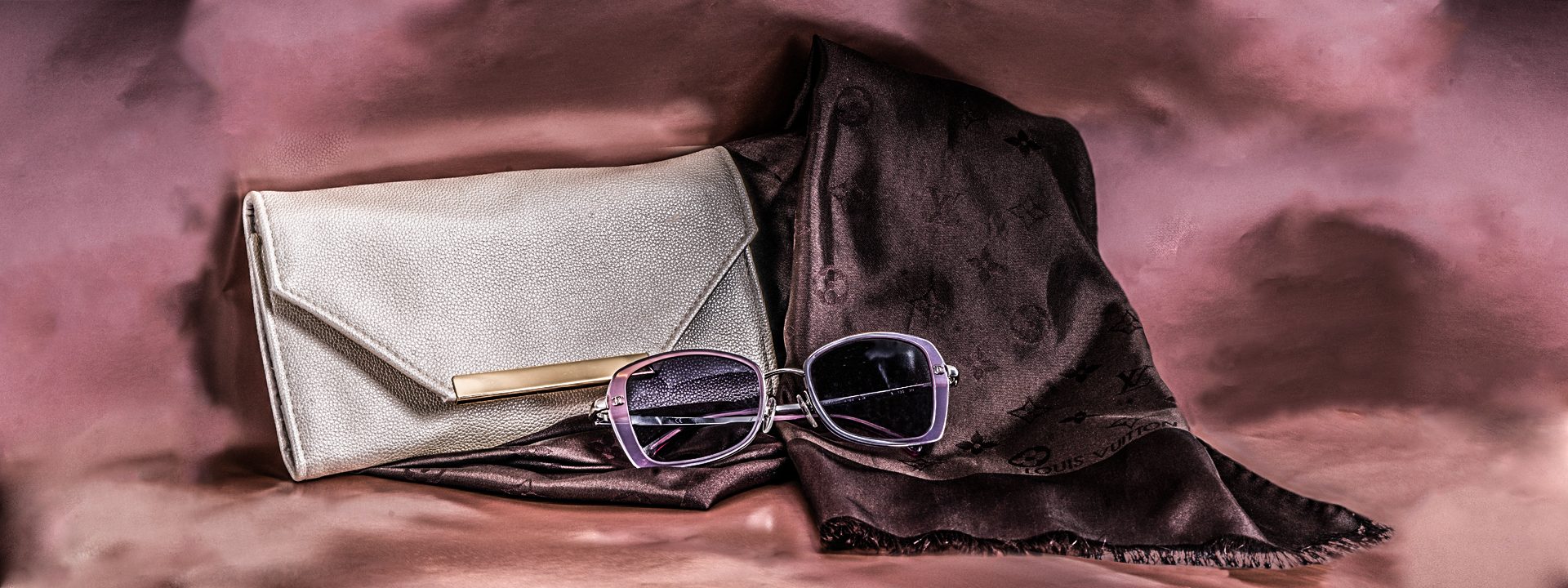 Vintage Chanel sunglasses, Louis Vuitton scarf, and jewelry clutch on pink velvet background.