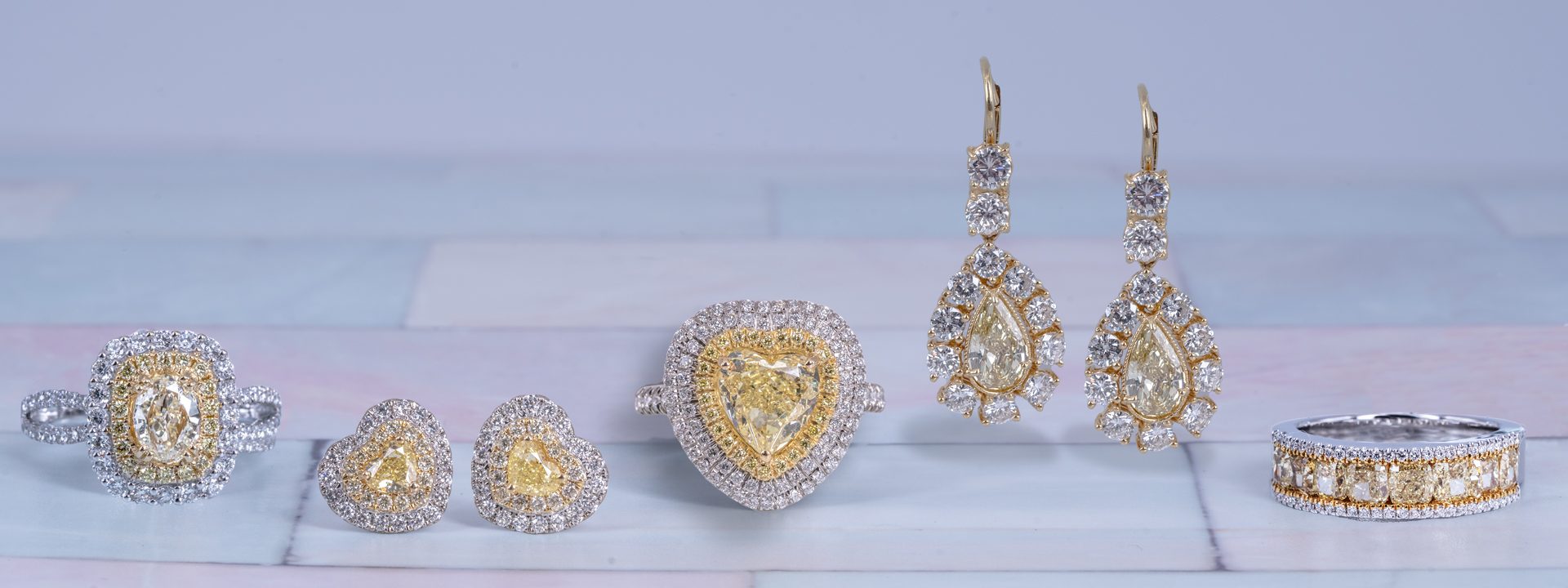 Drop earrings, stud earrings, and three rings all set with yellow diamonds surrounded by white diamonds.