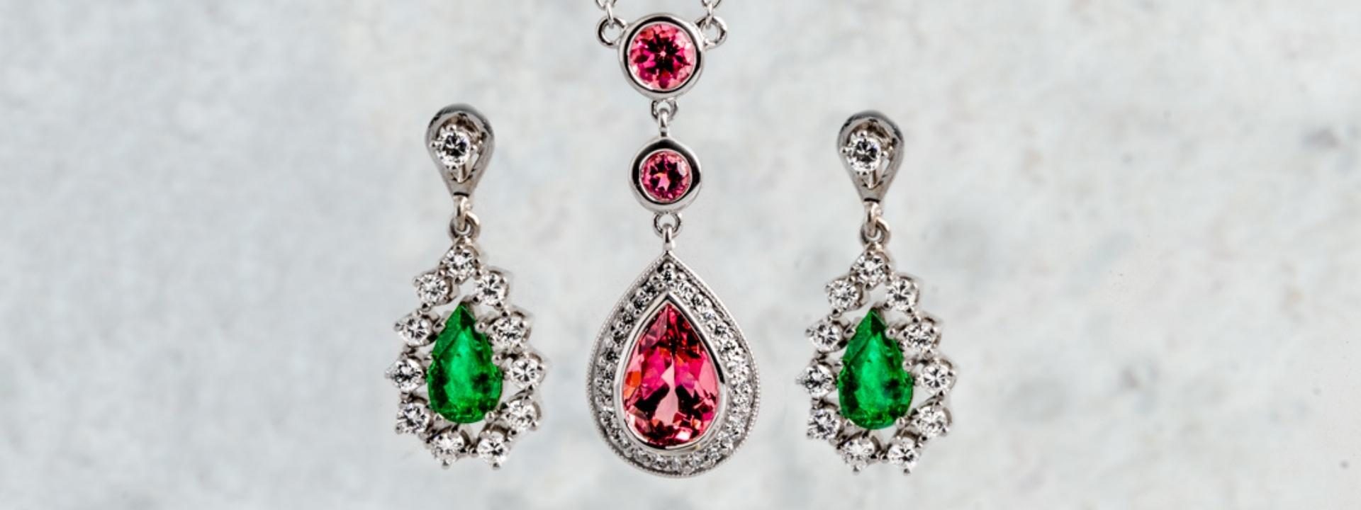 White gold pear cut drop earrings and necklace both set with gemstones surrounded by diamond haloes.