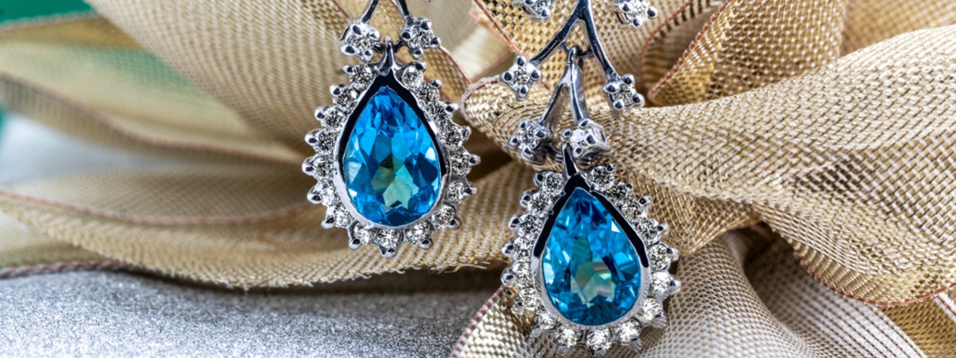 White gold vine drop earrings set with pear cut blue topaz and diamond haloes.