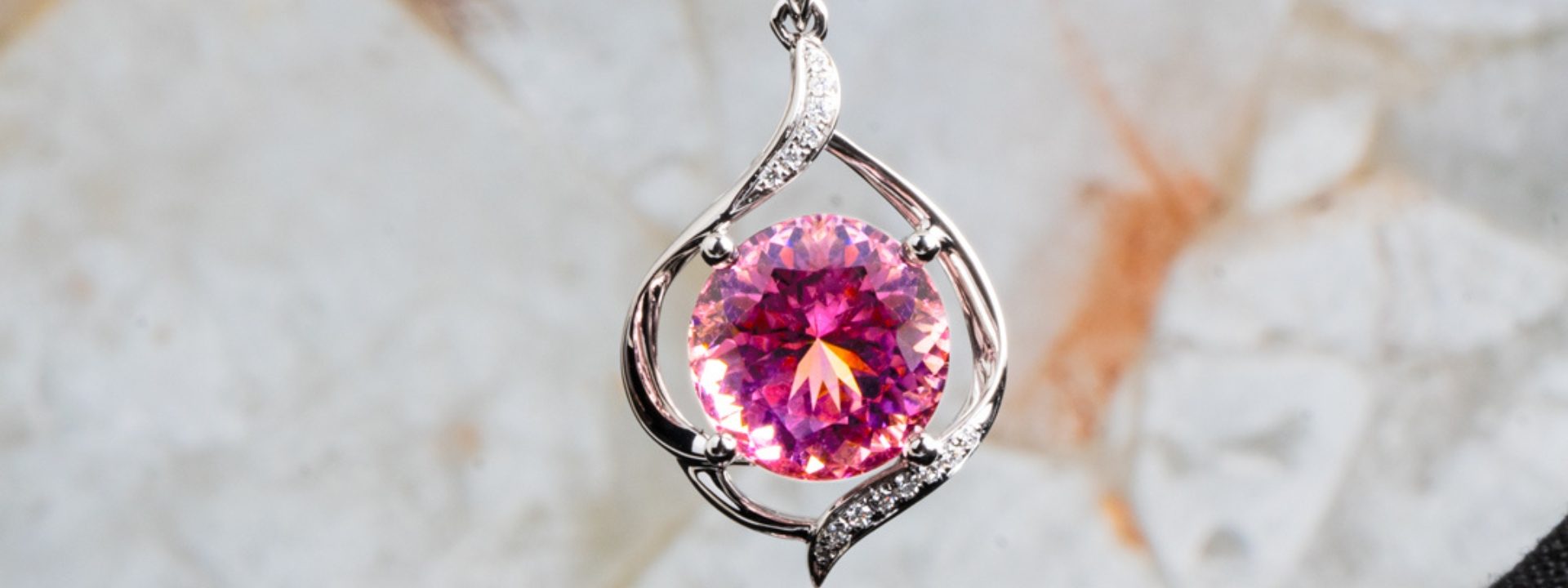 Yellow gold open style pink tourmaline pendant with surrounding diamonds.