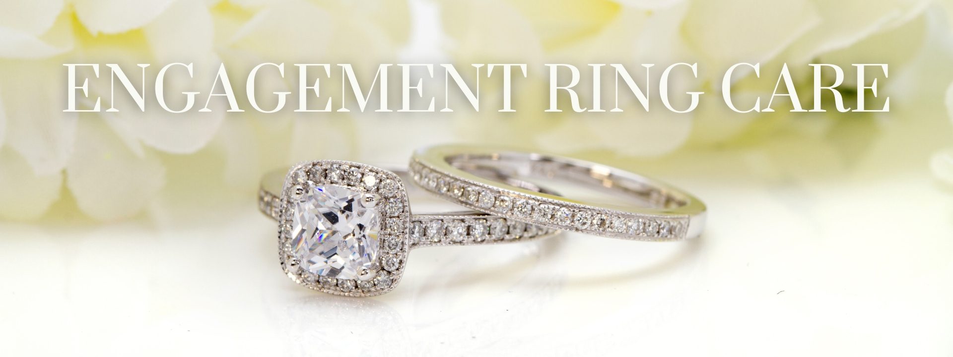 White gold diamond engagement ring with a diamond halo and diamonds in the band with a diamond wedding band stacked on top in front of a green floral background with text, Engagement Ring Care.