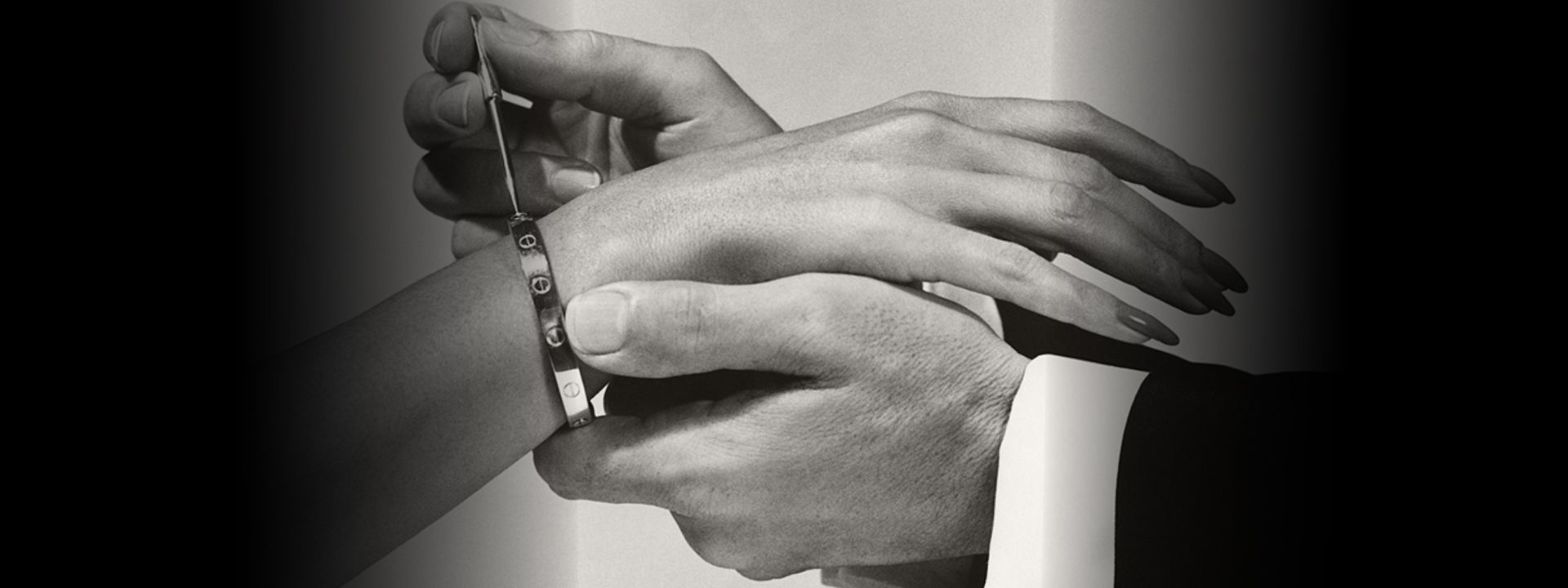 Man fastening a Cartier LOVE bracelet on a woman’s wrist with the Cartier screwdriver.