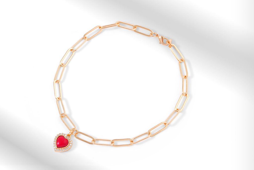 Yellow gold oval link bracelet with red enamel heart charm.