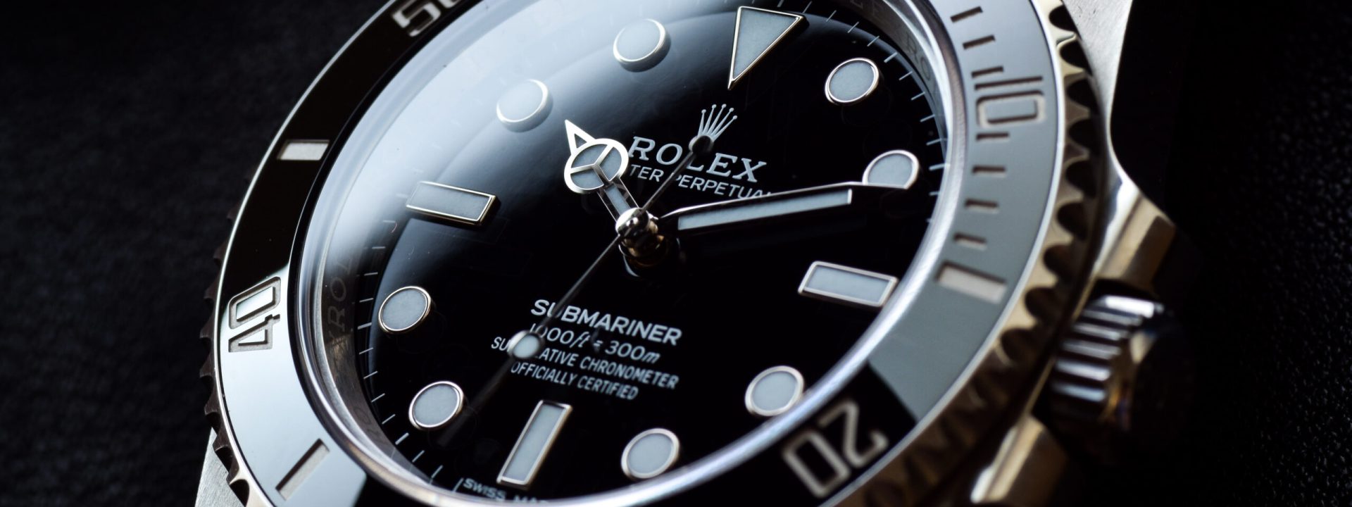 Close-up of a Rolex Submariner in stainless steel with a black dial, white markers, and a black ceramic bezel.