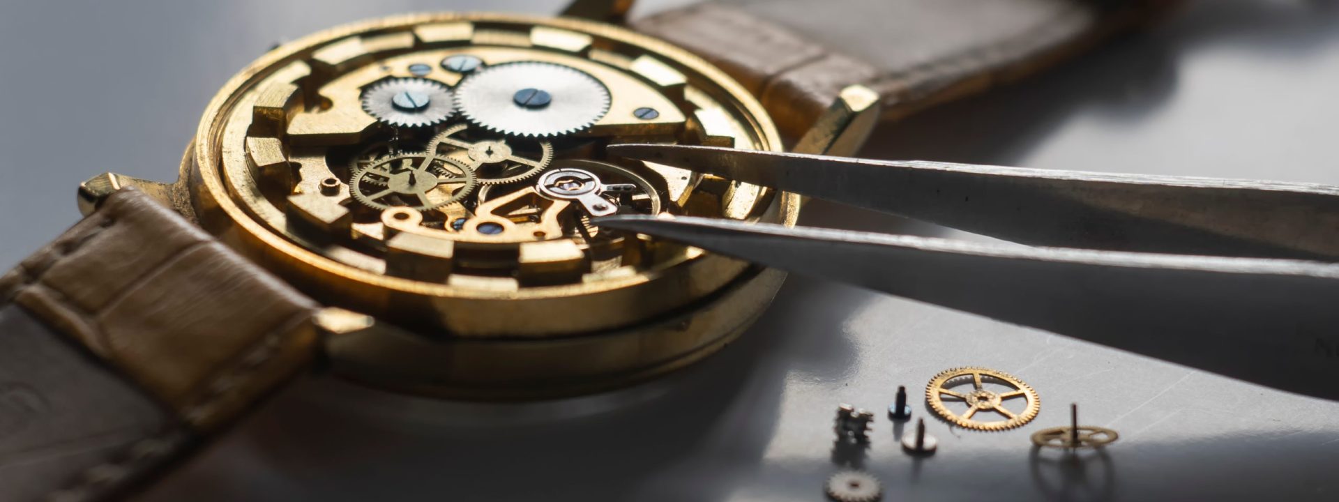 Watchmaker using tweezers to work on inner gears and crystals of a fine watch.