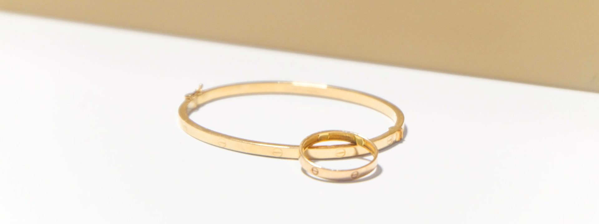 Vintage Cartier LOVE ring in yellow gold stacked on a vintage Cartier LOVE bracelet in yellow gold.