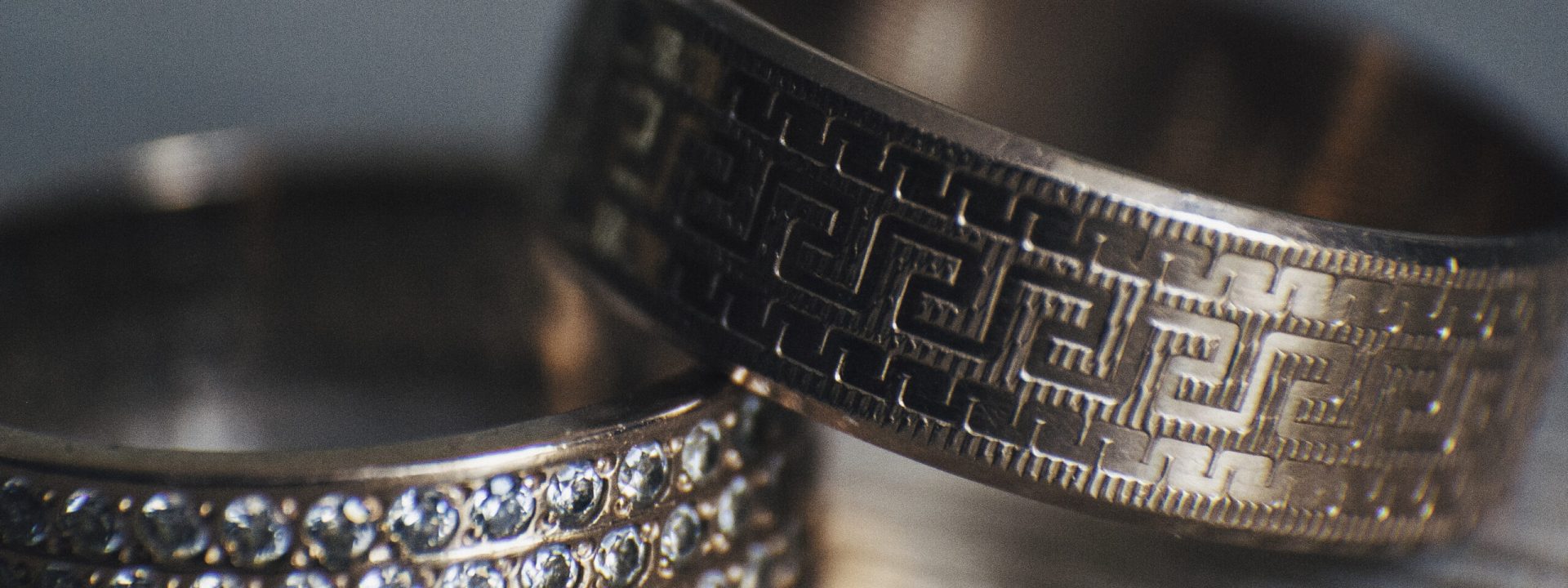 Two yellow gold men's wedding bands stacked on a wooden table.